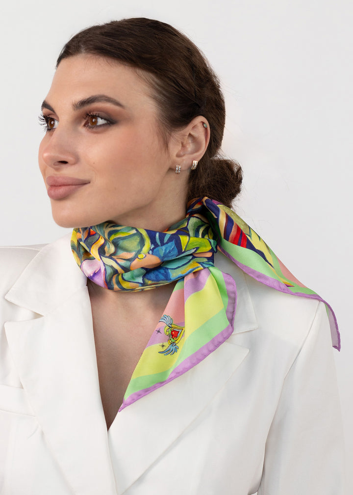 Elegante Frau trägt das quadratische Designer Seidentuch Zauberwald Morgen 65×65 cm aus Twill-Seide, seitlich am Hals geknotet, mit buntem Blumenmotiv und zartem Pastellrand