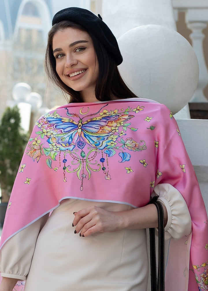 Frau trägt den Designer-Seidenschal „Geschenk fuer Frauen Seidenschal Schmetterling“ in Rosé  Seidentuch mit Schmetterlingsmotiv und floralen Details, über die Schultern gelegt, Design von Iryna Feinblatt.
