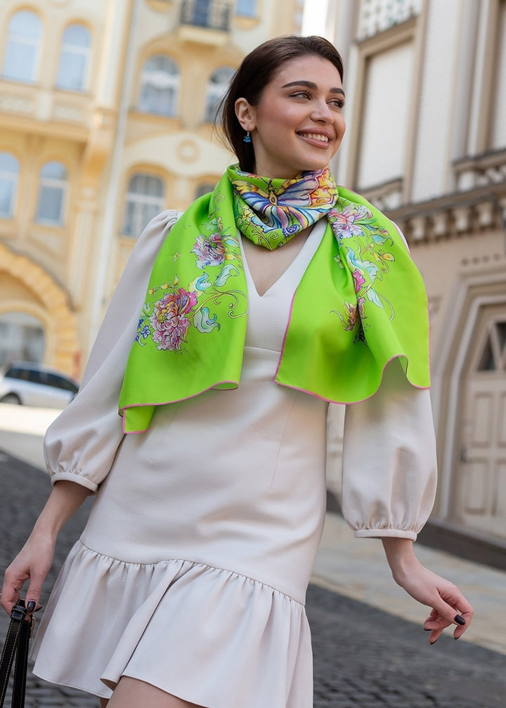Designer-Seidenschal mit Schmetterlingsmotiv  hellgrüner Seidenschal mit Schmetterling und floralen Details, als Halstuch getragen, Frau in hellem Kleid, Iryna Feinblatt Design.
