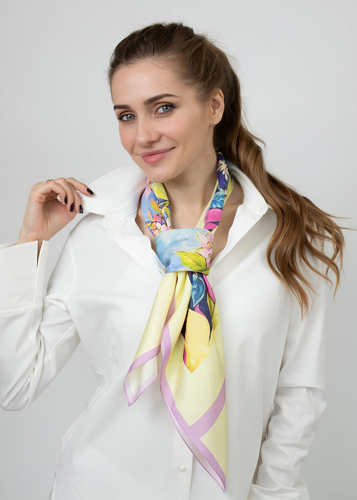 Designer Seidentuch „Zauberwald Morgen“ 90×90 cm aus 100 % Twill-Seide – luxuriöser Seidenschal mit handgemaltem floralen Muster in Blau, Gelb und Rosa, elegant gebunden über weißer Bluse – Feinblatt
