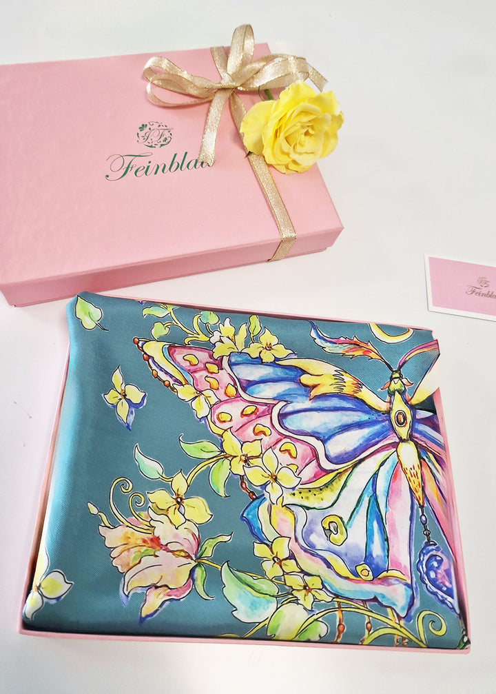 Designer Seidenschal „Emerald Butterfly“ in Smaragdgrün – luxuriös verpackt in rosa Geschenkbox mit gelber Blume und goldener Schleife. Exklusives Design von Iryna Feinblatt, Kunst auf Twill-Seide.
