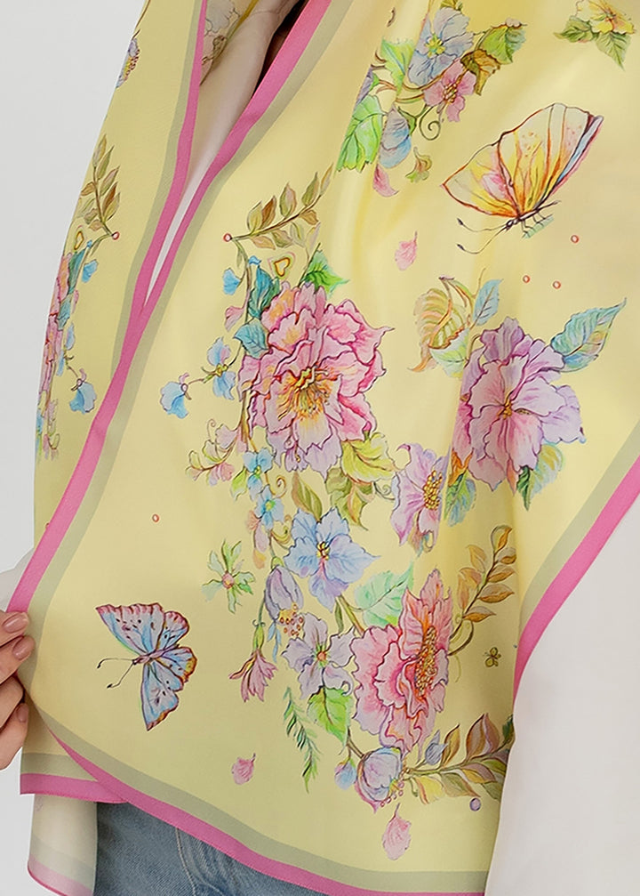 Nahaufnahme des Seidenkopftuchs „Herz aus Blumen in Gelb“ von Iryna Feinblatt – handgezeichnete Blumen und Schmetterlinge auf gelber Seide.