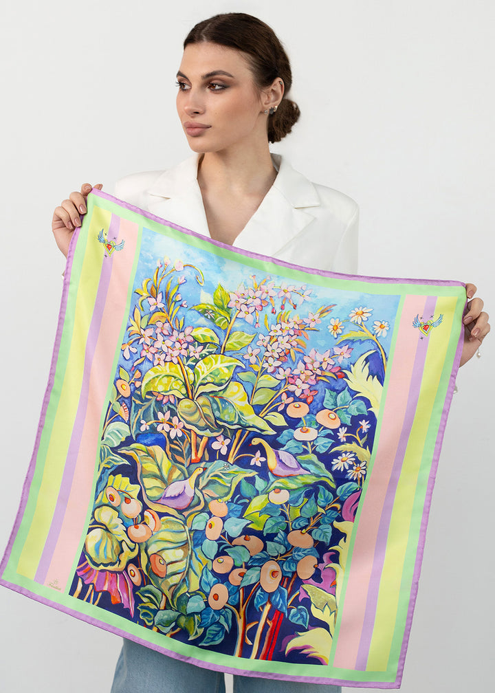 Frau präsentiert Designer Seidentuch Zauberwald Morgen“65×65 cm aus Twill-Seide, geöffnet mit Blumen- und Vogelmotiv, Pastellrand und fliegenden Herzen