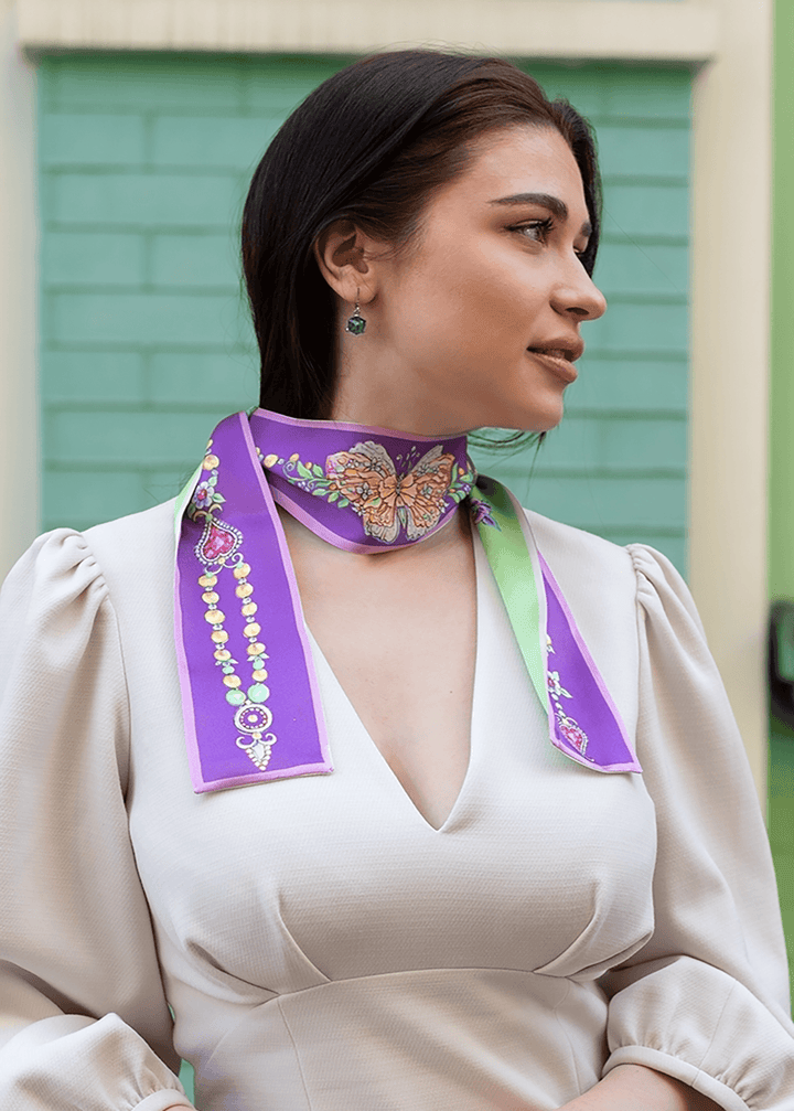 Edler Seidenschal in Lila und Mintgrün mit handgemaltem Schmetterlings- und Juwelenmotiv, elegant um den Hals einer Frau getragen – luxuriöses Accessoire für besondere Anlässe und stilvolle Outfits
