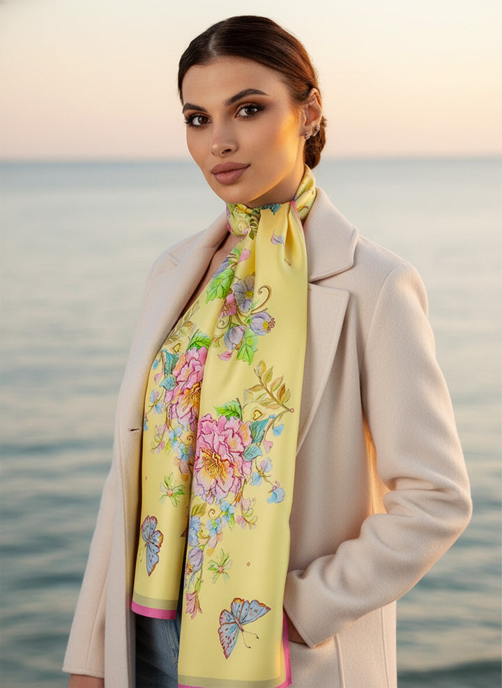 Frau trägt das Seidenkopftuch „Herz aus Blumen in Gelb“ von Iryna Feinblatt – zarte Seide mit Blumenmotiv im warmen Abendlicht am Meer.