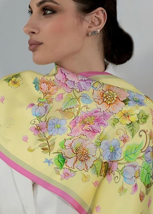 Frau trägt das Seidenkopftuch „Herz aus Blumen in Gelb“ von Iryna Feinblatt über den Schultern – florales Design auf zarter gelber Seide.